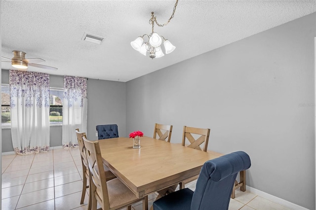 dining space with ceiling fan with notable chandelier, a textured ceiling, and light tile patterned flooring