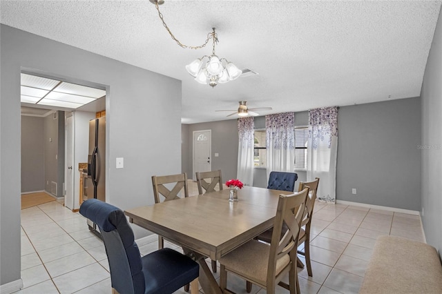 tiled dining room with ceiling fan with notable chandelier and a textured ceiling