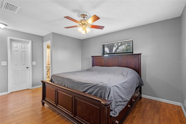 bedroom with hardwood / wood-style flooring, ceiling fan, and a textured ceiling