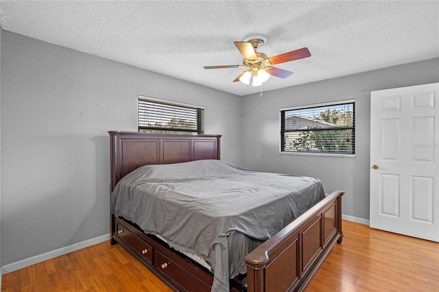 bedroom featuring ceiling fan, a textured ceiling, and light wood-type flooring