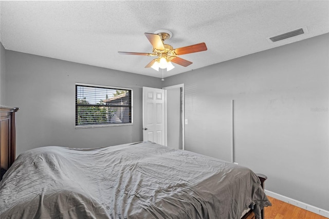 bedroom with hardwood / wood-style flooring, a textured ceiling, and ceiling fan