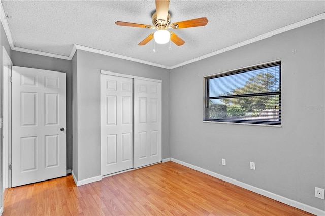 unfurnished bedroom with crown molding, ceiling fan, light hardwood / wood-style floors, a textured ceiling, and a closet