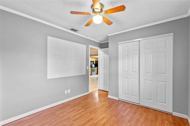 unfurnished bedroom featuring light hardwood / wood-style flooring, ceiling fan, ornamental molding, a textured ceiling, and a closet