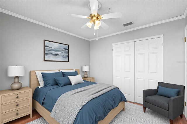 bedroom with hardwood / wood-style flooring, ornamental molding, a closet, and ceiling fan