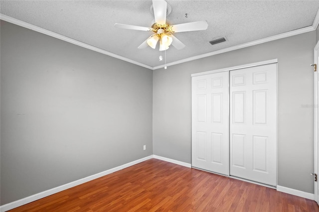 unfurnished bedroom with ornamental molding, wood-type flooring, and a textured ceiling