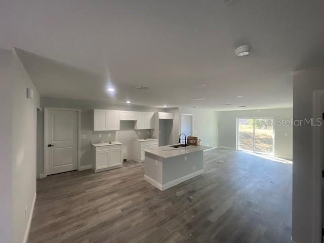 kitchen featuring a kitchen island with sink, hardwood / wood-style floors, sink, and white cabinets