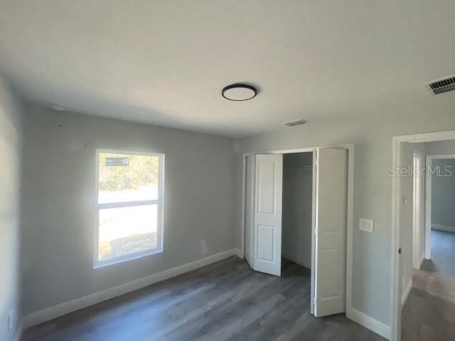 unfurnished bedroom with dark hardwood / wood-style flooring and a closet