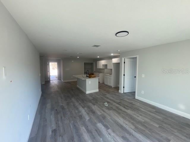 kitchen with an island with sink, sink, white cabinets, and dark hardwood / wood-style flooring