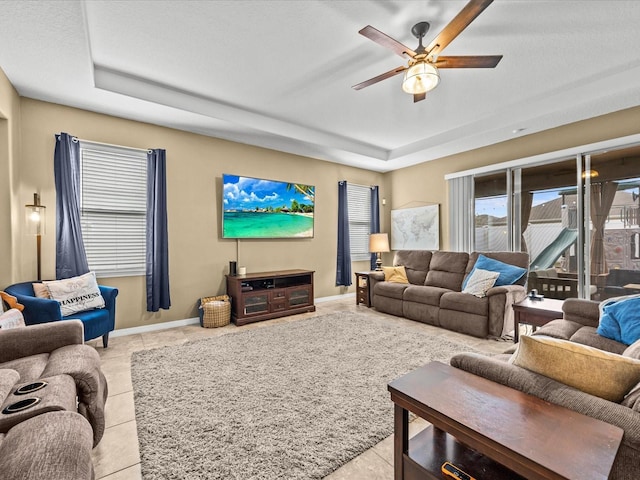 living room featuring light tile patterned floors, a raised ceiling, and ceiling fan