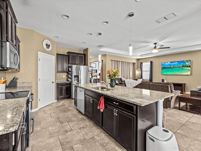 kitchen with sink, decorative light fixtures, dark brown cabinets, a center island with sink, and appliances with stainless steel finishes