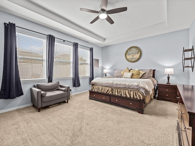 bedroom featuring a raised ceiling, light carpet, and ceiling fan