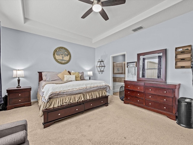 carpeted bedroom featuring a tray ceiling, ceiling fan, and ensuite bathroom