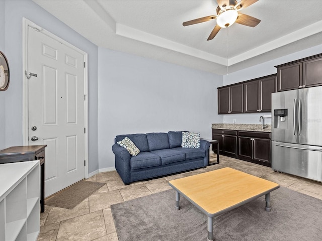 living room featuring sink, ceiling fan, and a tray ceiling