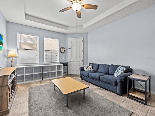 living room featuring ceiling fan and a raised ceiling