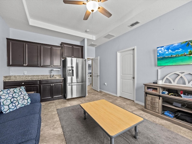 living room featuring ceiling fan, sink, and a textured ceiling