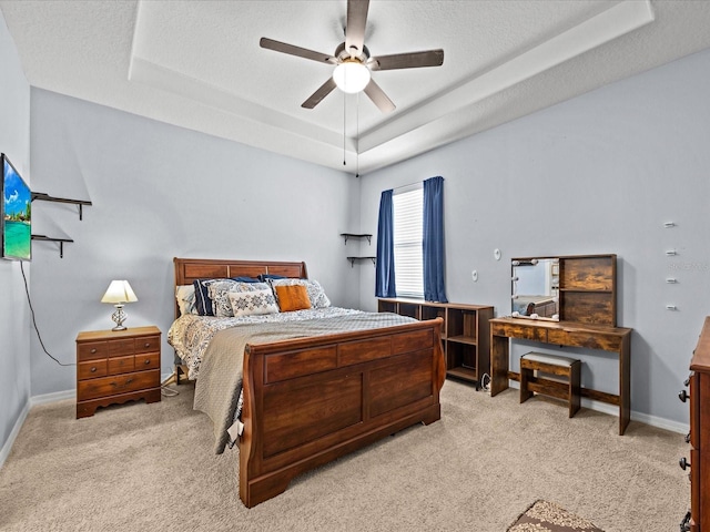 carpeted bedroom featuring ceiling fan, a tray ceiling, and a textured ceiling