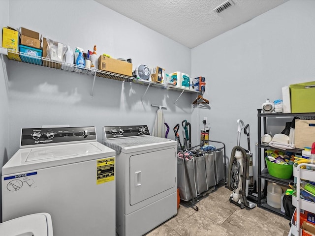 laundry room with a textured ceiling and washing machine and clothes dryer