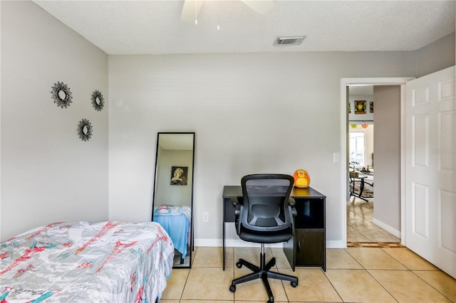 bedroom featuring ceiling fan, a textured ceiling, and light tile patterned floors