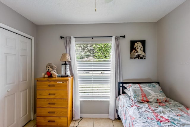 tiled bedroom featuring a textured ceiling and a closet