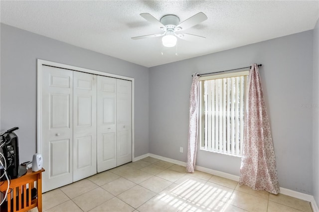 bedroom featuring ceiling fan, a closet, a textured ceiling, and light tile patterned flooring