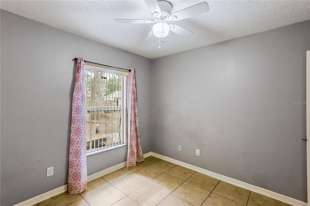 tiled spare room with a textured ceiling and ceiling fan