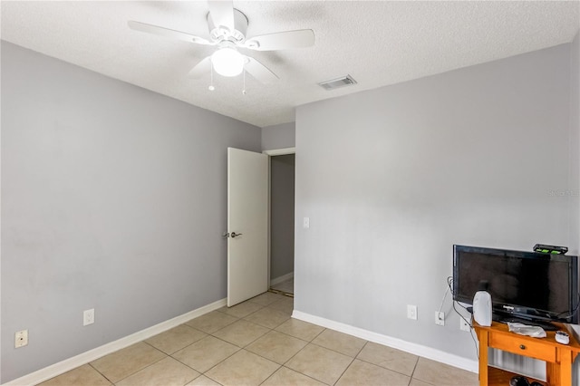 interior space featuring light tile patterned floors, a textured ceiling, and ceiling fan