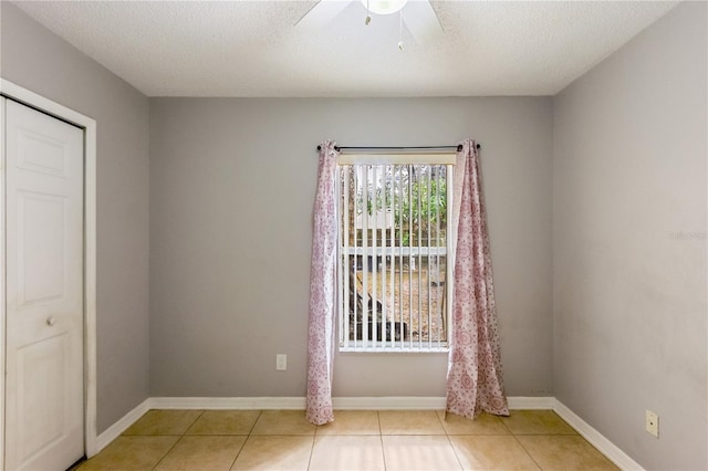 tiled empty room with a textured ceiling and ceiling fan