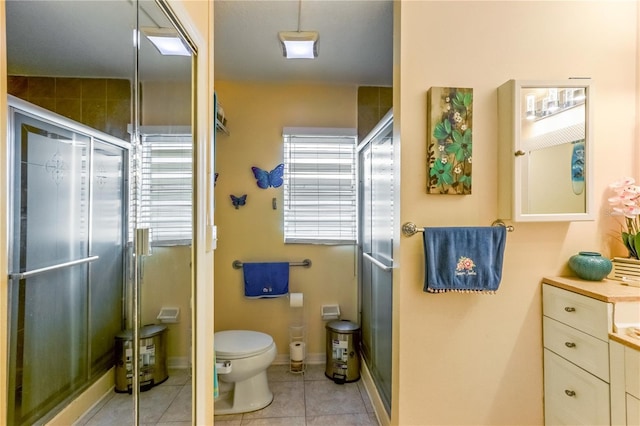 bathroom with tile patterned floors, vanity, toilet, and a shower with door