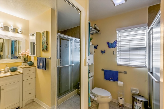 bathroom featuring walk in shower, vanity, toilet, and tile patterned flooring