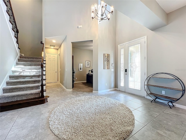 foyer with light tile patterned flooring, a towering ceiling, and an inviting chandelier