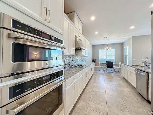 kitchen with sink, stone countertops, appliances with stainless steel finishes, white cabinets, and backsplash