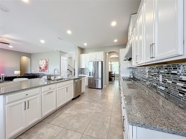 kitchen featuring sink, appliances with stainless steel finishes, stone counters, a large island, and white cabinets