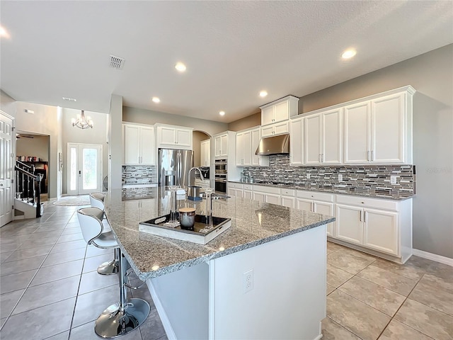 kitchen with white cabinetry, stainless steel appliances, a spacious island, and a kitchen bar