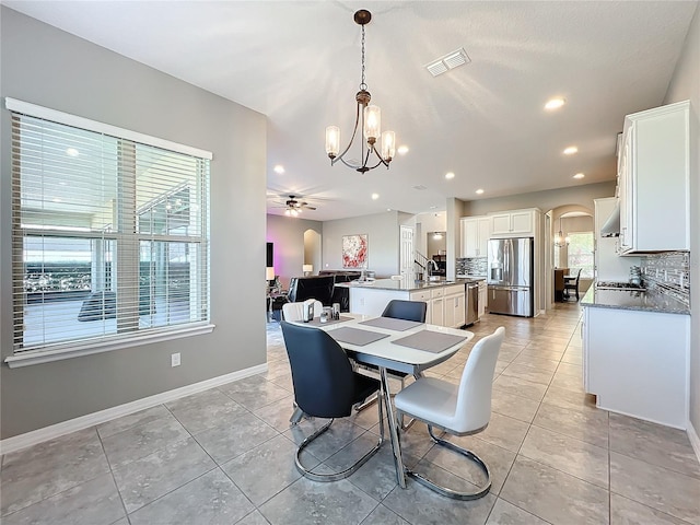 dining room with ceiling fan with notable chandelier, sink, and light tile patterned floors