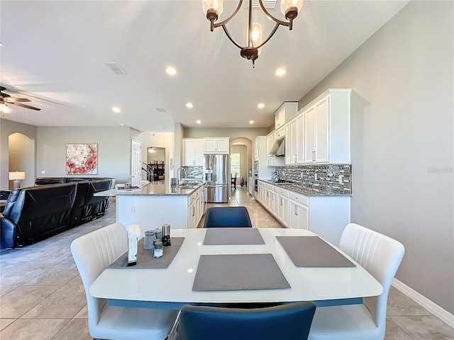 dining area featuring ceiling fan with notable chandelier, sink, and light tile patterned floors