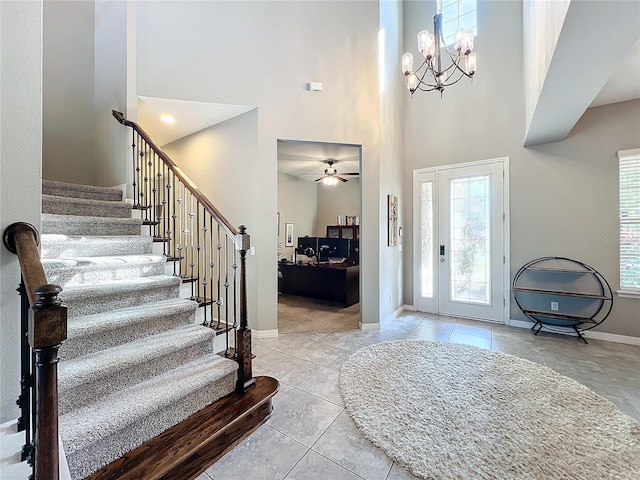 entryway with a towering ceiling, light tile patterned floors, and an inviting chandelier