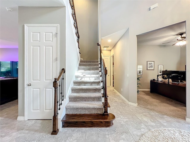 staircase featuring tile patterned flooring and ceiling fan