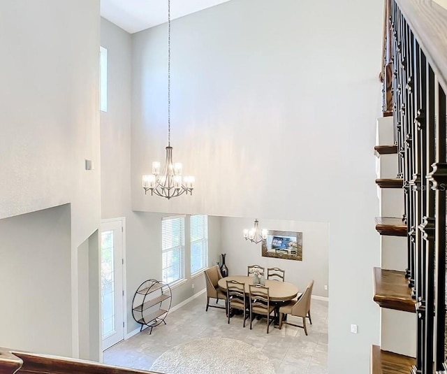 dining room featuring an inviting chandelier and a towering ceiling