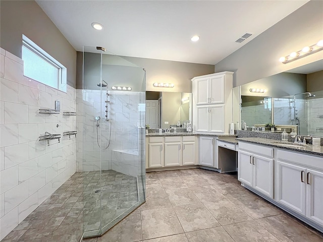 bathroom with a tile shower and vanity