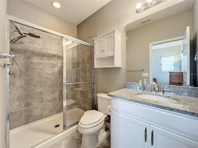 bathroom featuring vanity, toilet, a shower with door, and a textured ceiling