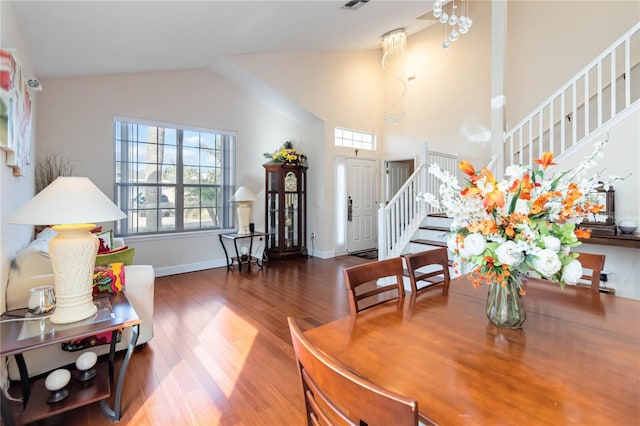 dining room with a healthy amount of sunlight, dark wood-type flooring, and high vaulted ceiling