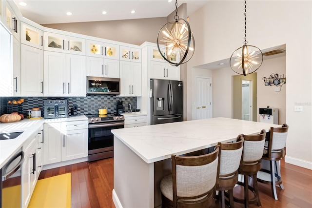 kitchen with hanging light fixtures, stainless steel appliances, a center island, a notable chandelier, and white cabinets