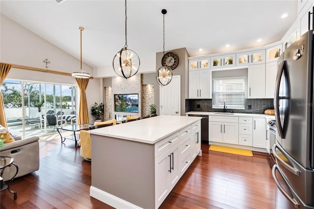 kitchen featuring sink, decorative light fixtures, a center island, stainless steel fridge, and white cabinets