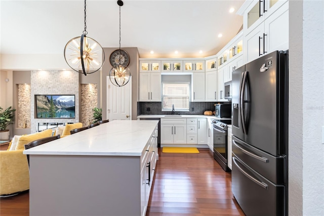 kitchen with white cabinetry, sink, hanging light fixtures, stainless steel appliances, and light stone countertops