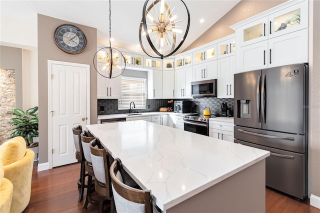 kitchen with stainless steel appliances, white cabinetry, a kitchen island, and hanging light fixtures