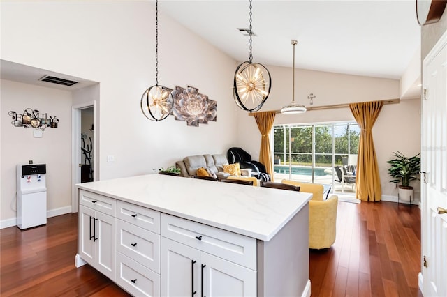 kitchen featuring dark wood-type flooring, light stone counters, hanging light fixtures, and white cabinets