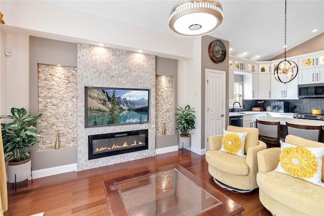 living room featuring lofted ceiling, sink, wood-type flooring, and a large fireplace