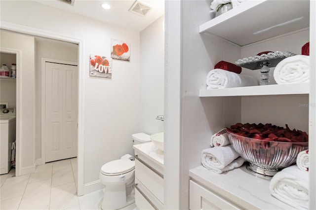 bathroom featuring vanity, washer / dryer, and toilet