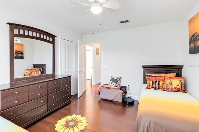 bedroom with ceiling fan, dark hardwood / wood-style floors, and a fireplace