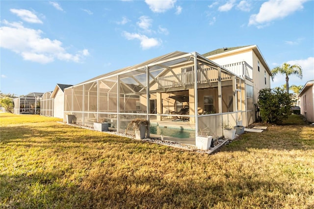 back of property featuring a lawn and glass enclosure